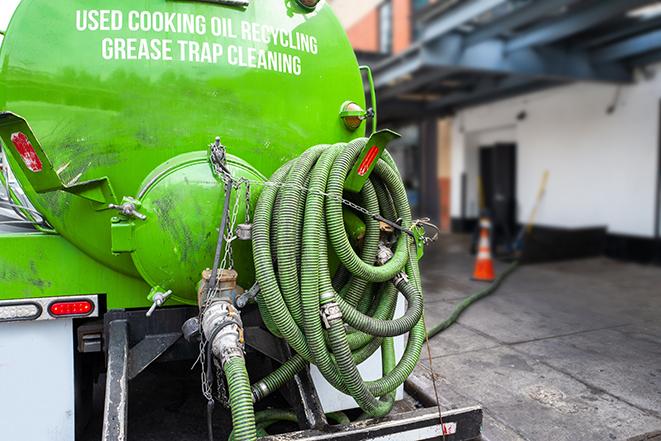 worker pumping grease trap at commercial kitchen in Fischer