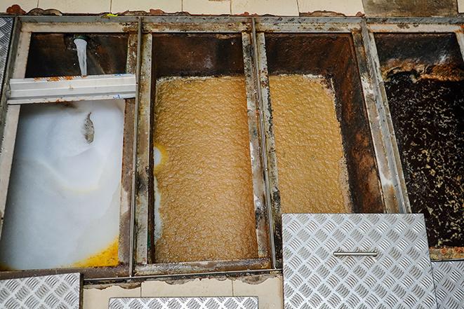 a professional cleaning crew performing maintenance on a grease trap